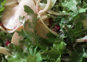 Close-up of greens, sliced pear and pomegranate
