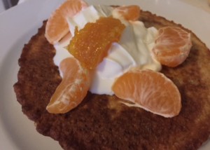Oatmeal Pancakes topped with cream and mandarine orange slices.