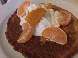 Oatmeal Pancakes topped with cream and mandarine orange slices.